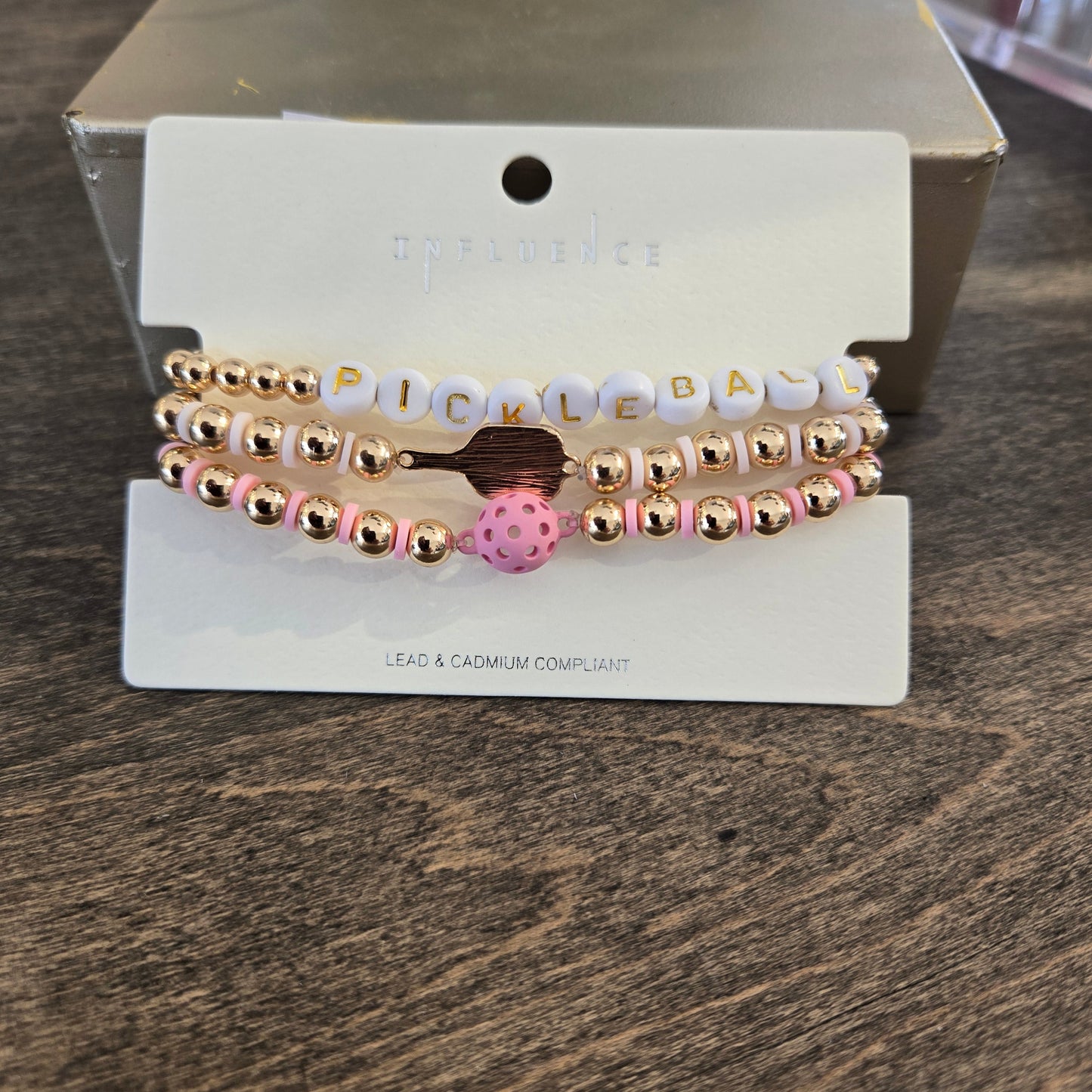 A set of three beaded stretch bracelets. The bracelets feature rose gold metallic beads, white letter beads spelling 'PICKLEBA', and a pink polka dot charm.